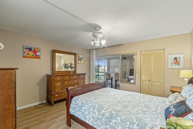 bedroom with ceiling fan, a textured ceiling, and light wood-type flooring