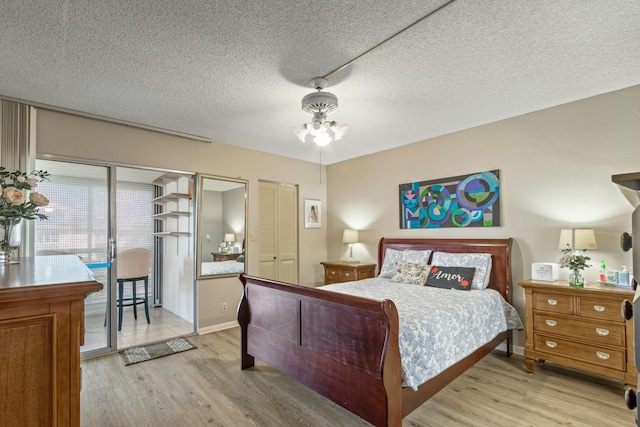 bedroom with access to exterior, a textured ceiling, and light hardwood / wood-style flooring