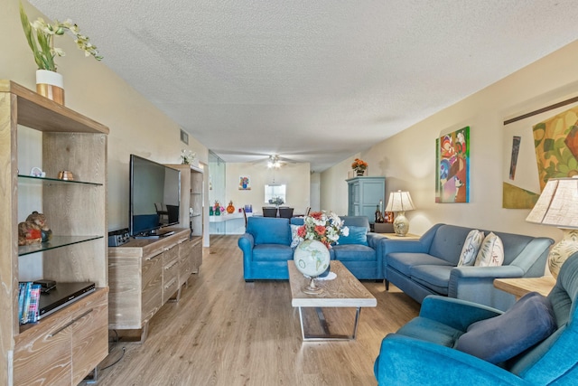 living room with ceiling fan, light hardwood / wood-style floors, and a textured ceiling