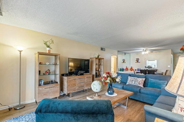 living room with ceiling fan, a textured ceiling, and hardwood / wood-style flooring