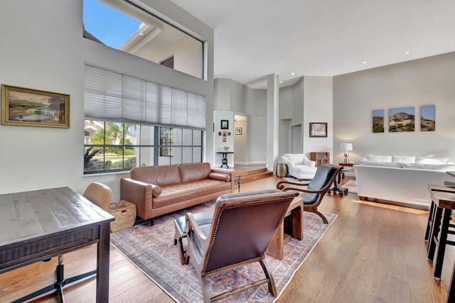 living room with a towering ceiling and hardwood / wood-style flooring