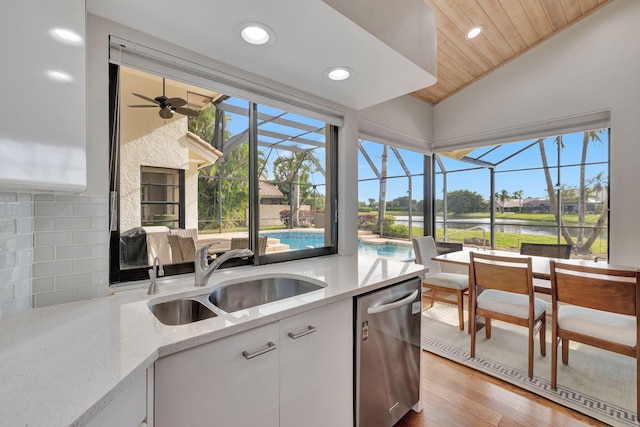 kitchen with light stone countertops, white cabinetry, sink, wooden ceiling, and stainless steel dishwasher