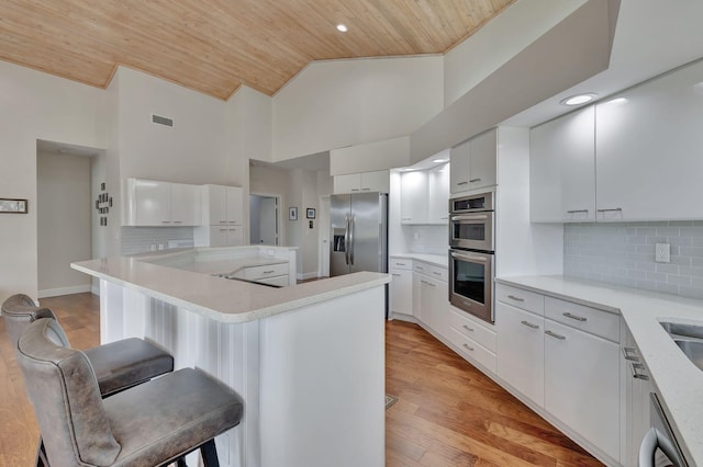 kitchen featuring stainless steel appliances, white cabinetry, a breakfast bar, and wood ceiling