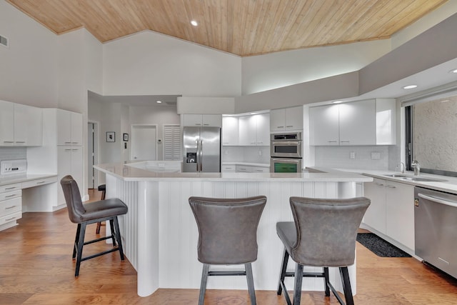 kitchen featuring a breakfast bar area, wooden ceiling, high vaulted ceiling, and stainless steel appliances