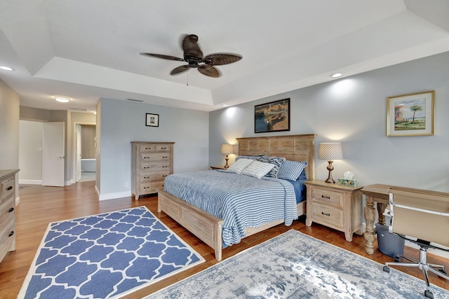 bedroom with a raised ceiling, ceiling fan, and hardwood / wood-style floors