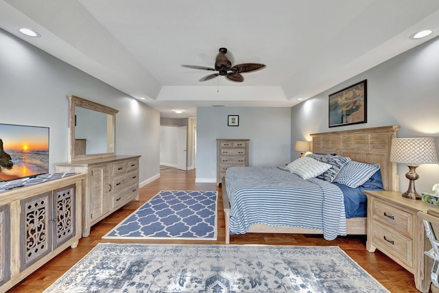 bedroom featuring hardwood / wood-style flooring, ceiling fan, and a raised ceiling