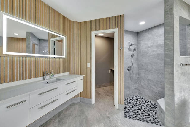 bathroom with a tile shower and vanity