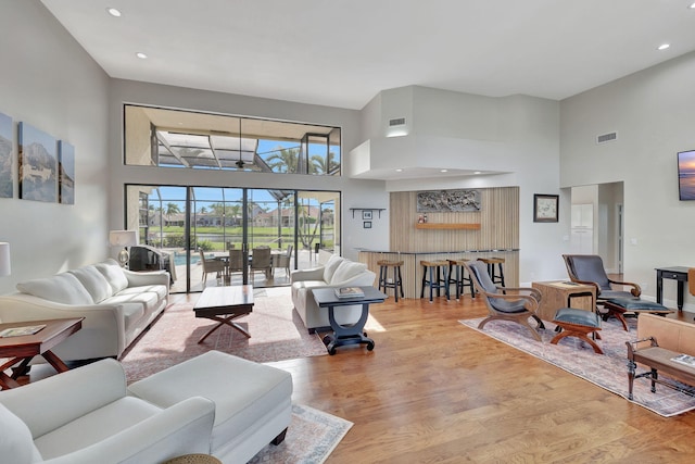 living room with light wood-type flooring and a towering ceiling