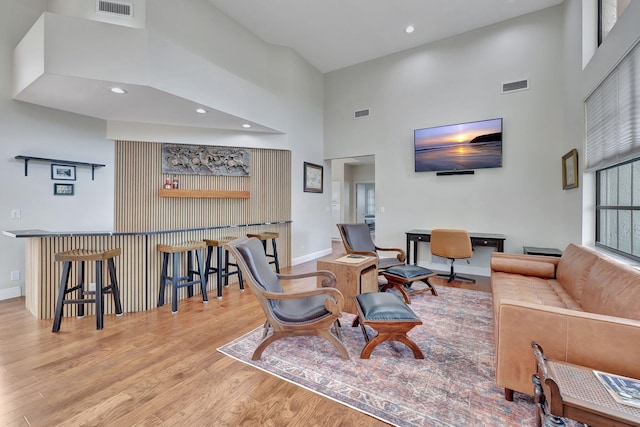 living room featuring a towering ceiling and light hardwood / wood-style flooring