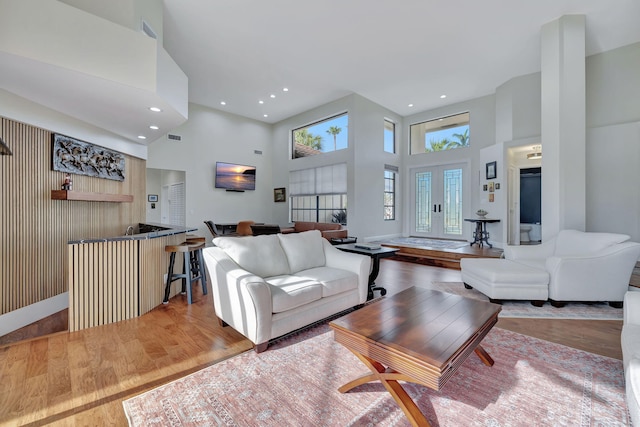 living room with wood-type flooring and a towering ceiling