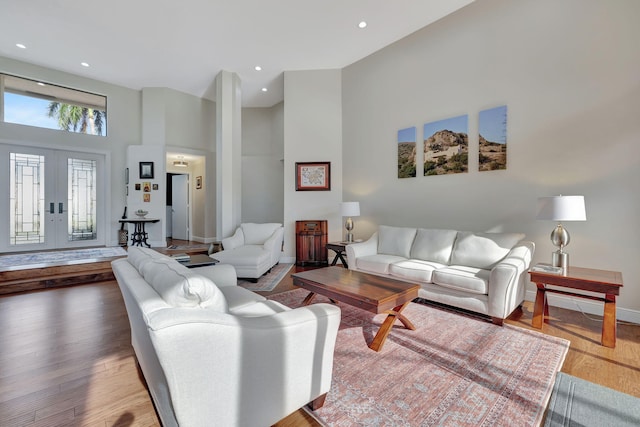 living room featuring hardwood / wood-style flooring, a towering ceiling, and french doors