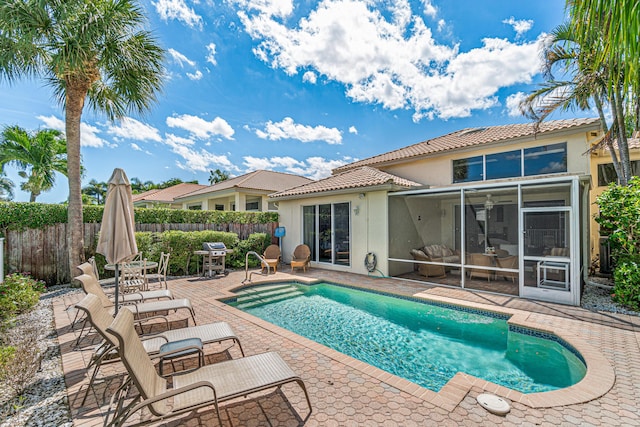 view of pool featuring grilling area, a patio area, and a sunroom