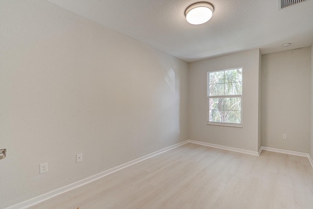 empty room with a textured ceiling and light wood-type flooring