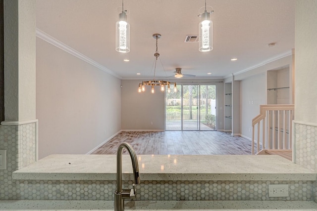 kitchen with light stone countertops, pendant lighting, and crown molding