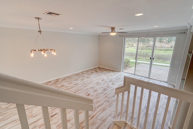 unfurnished room with a textured ceiling, light hardwood / wood-style flooring, ceiling fan with notable chandelier, and ornamental molding