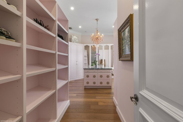 spacious closet featuring a chandelier and wood-type flooring