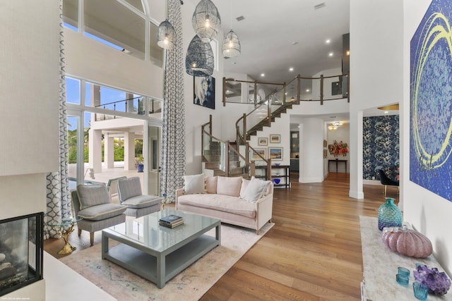 living room featuring a towering ceiling, a multi sided fireplace, and hardwood / wood-style floors