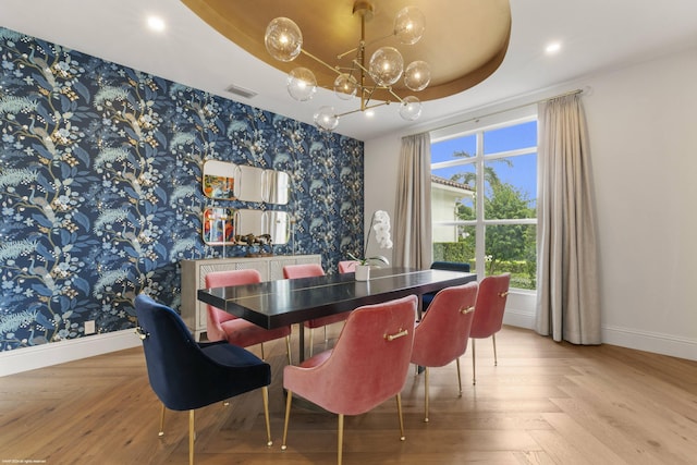 dining space with a raised ceiling, parquet floors, and an inviting chandelier