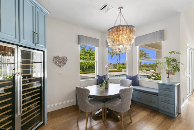 dining space with wine cooler, an inviting chandelier, and hardwood / wood-style flooring