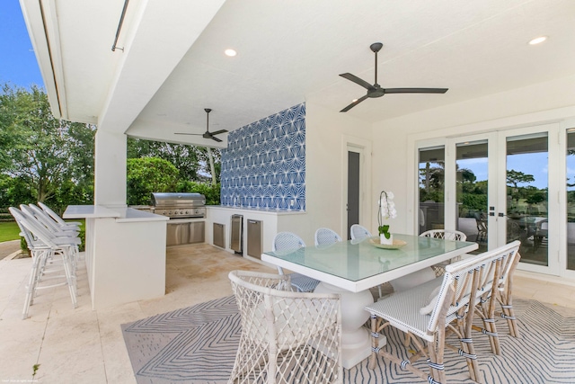 view of patio / terrace with a bar, ceiling fan, an outdoor kitchen, french doors, and area for grilling