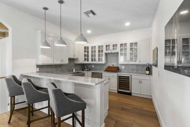 kitchen with a breakfast bar area, wine cooler, white cabinets, and kitchen peninsula