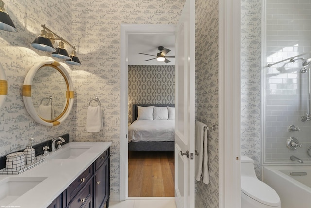 full bathroom with ceiling fan, toilet, vanity, and tiled shower / bath combo