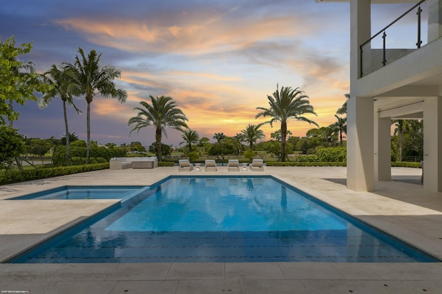 pool at dusk with a patio area