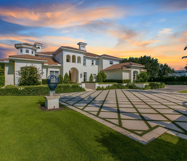 back house at dusk with a lawn