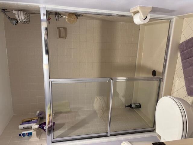 bathroom featuring a shower with shower door and toilet