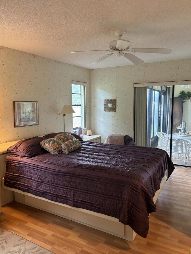 bedroom featuring access to exterior, ceiling fan, a textured ceiling, and hardwood / wood-style flooring