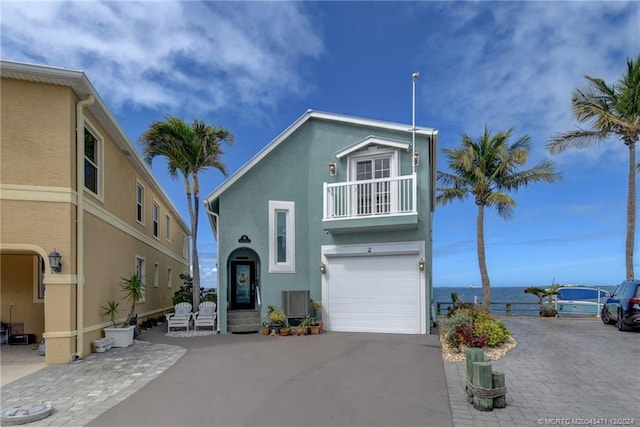 view of front of home with a balcony, a garage, and a water view