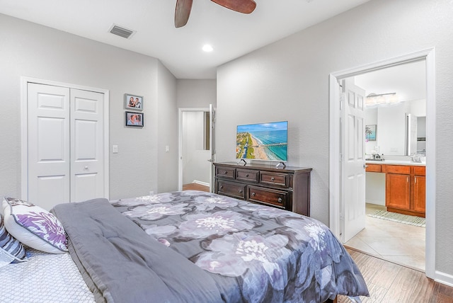 bedroom featuring ceiling fan, a closet, light hardwood / wood-style flooring, and ensuite bath