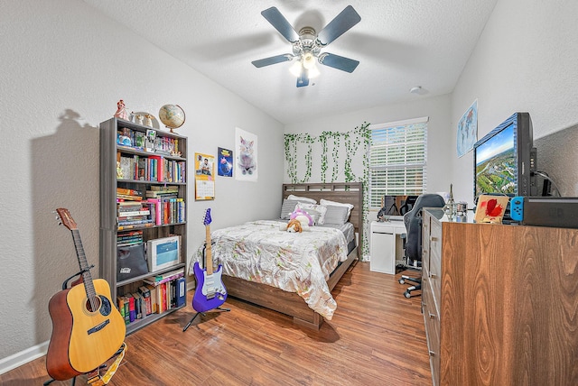 bedroom with hardwood / wood-style floors, a textured ceiling, and ceiling fan