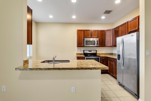 kitchen with sink, light stone countertops, appliances with stainless steel finishes, light tile patterned flooring, and kitchen peninsula