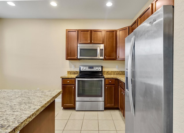 kitchen with light stone countertops, light tile patterned floors, and stainless steel appliances