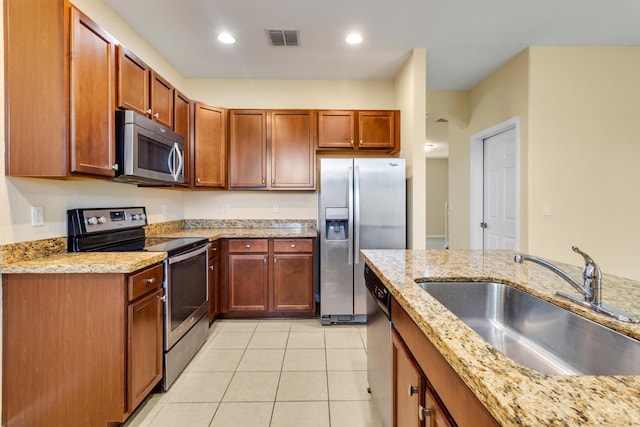 kitchen featuring light stone counters, sink, light tile patterned floors, and appliances with stainless steel finishes