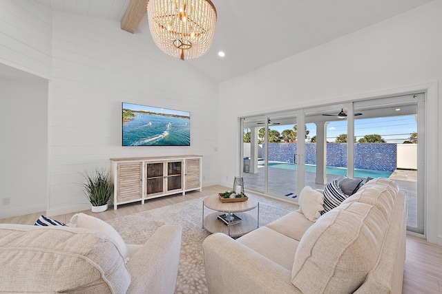 living room with beamed ceiling, ceiling fan with notable chandelier, light hardwood / wood-style flooring, and high vaulted ceiling