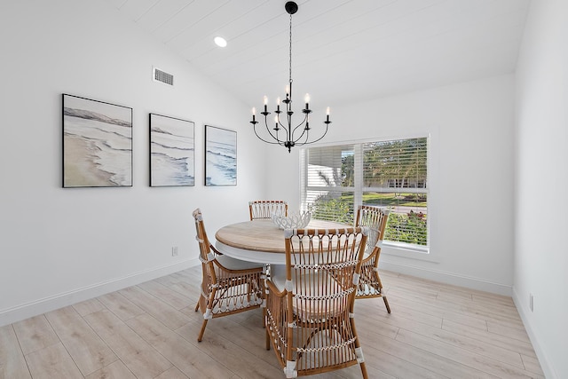 dining area with lofted ceiling, light wood-type flooring, and a chandelier