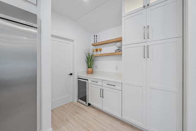 kitchen with white cabinets, stainless steel built in fridge, beverage cooler, and vaulted ceiling