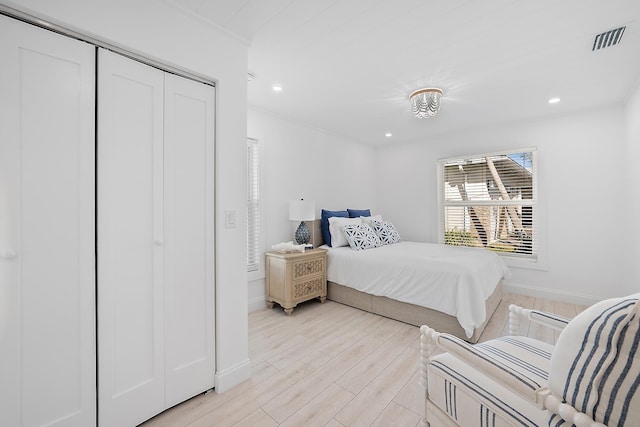 bedroom with light wood-type flooring, a closet, and ornamental molding