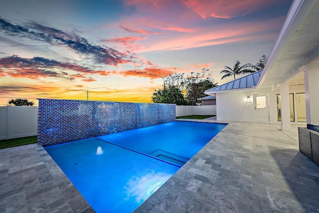 pool at dusk featuring a patio area