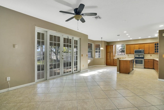 kitchen featuring pendant lighting, french doors, ceiling fan, appliances with stainless steel finishes, and a kitchen island