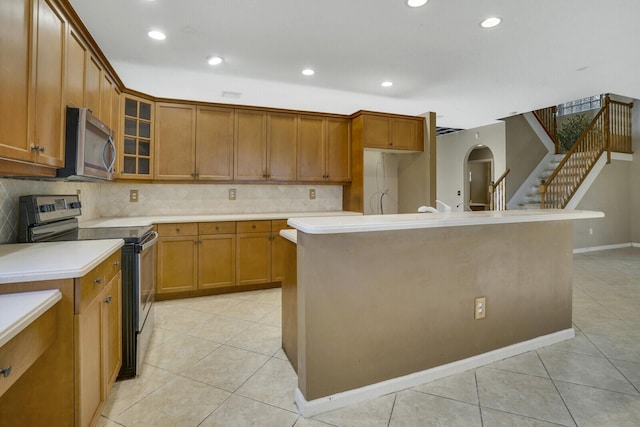 kitchen featuring light tile patterned floors, a center island, stainless steel appliances, and backsplash