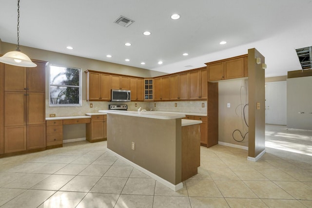 kitchen with decorative backsplash, pendant lighting, light tile patterned floors, range, and an island with sink