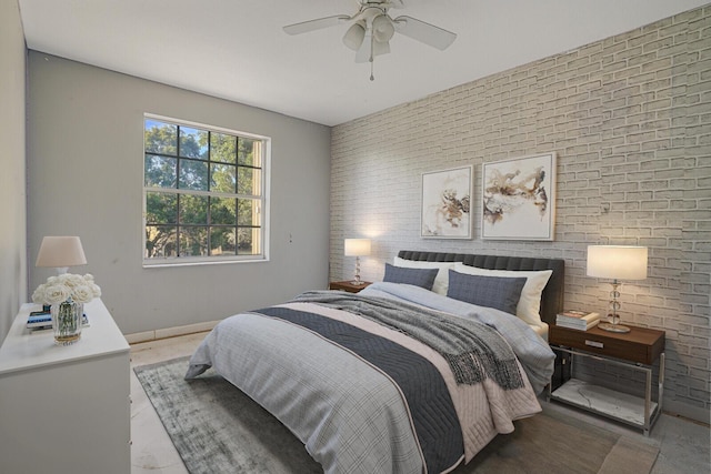 bedroom with ceiling fan and brick wall