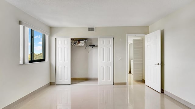 unfurnished bedroom with a closet, light tile patterned floors, and a textured ceiling