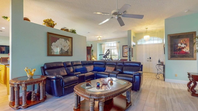 living room with ceiling fan, light hardwood / wood-style flooring, and a textured ceiling