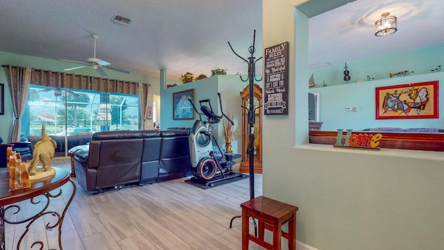 living room featuring lofted ceiling, ceiling fan, light hardwood / wood-style flooring, and a textured ceiling