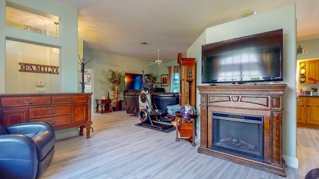 living room featuring a textured ceiling, light hardwood / wood-style flooring, and ceiling fan