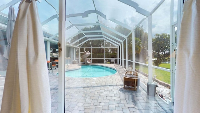 view of swimming pool featuring a patio, glass enclosure, and a fire pit